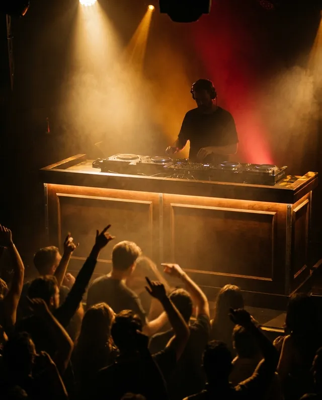 DJ com iluminação dourada e público